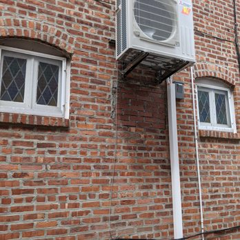 Mr Air Nyc - Outdoor Unit is strong enough for the entire basement. - A Mitsubishi outdoor HVAC unit is installed on a metal bracket on a brick wall, with two small windows nearby. - Heating & Air Conditioning/HVAC Near Me - Brooklyn, New York
