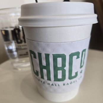 Crieve Hall Bagel - Seasonal latte in a to-go cup (water cup in the background) - Bagels Near Me - Nashville, Tennessee Crieve Hall Bagel - Seasonal latte in a to-go cup (water cup in the background) - Bagels Near Me - Nashville, Tennessee