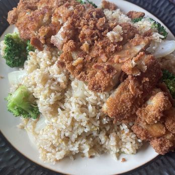 Little Thai Corner - Fried rice with crispy chicken - The image shows a plate of fried rice with pieces of crispy fried chicken on top. The dish includes broccoli florets and appears to be served in a restaurant or takeout setting. The fried chicken has a golden-brown, crunchy coating, and the rice looks fluffy and well-cooked. - Thai Near Me - Warwick, Rhode Island
