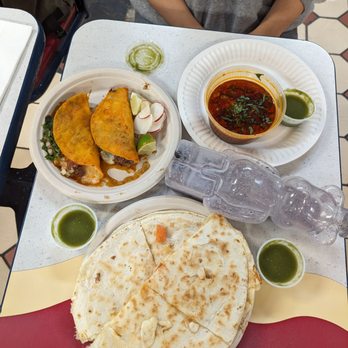 Two birria tacos with dipping sauce and large chicken quesadilla