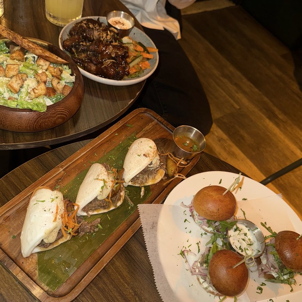 Guava BBQ wings, Caesar salad, lamb sliders, and oxtail bao buns.