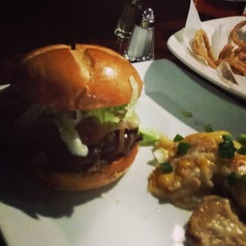 Lewis' - Burger with au gratin potatoes. Basket of onion rings in the background. - Sports Bars Near Me - Norwood, Massachusetts Lewis' - Burger with au gratin potatoes. Basket of onion rings in the background. - Sports Bars Near Me - Norwood, Massachusetts
