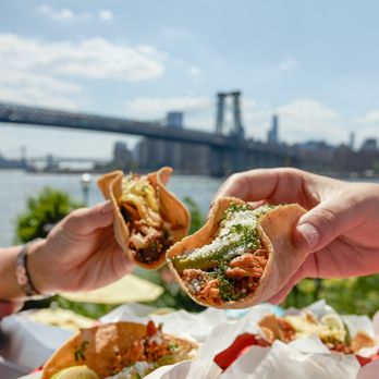 Tacocina - two hands holding a taco with a view of the brooklyn bridge in the background - Tacos Near Me - Brooklyn, New York Tacocina - two hands holding a taco with a view of the brooklyn bridge in the background - Tacos Near Me - Brooklyn, New York
