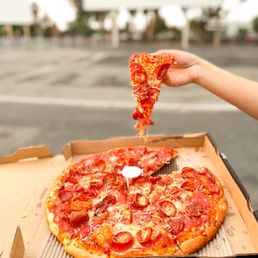 a hand holding a slice of pizza a hand holding a slice of pizza