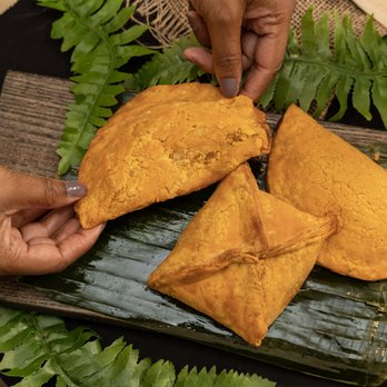 Gladys Caribbean Kitchen - a person grabbing a piece of food from a plate - Caribbean Near Me - Winnipeg, Manitoba Gladys Caribbean Kitchen - a person grabbing a piece of food from a plate - Caribbean Near Me - Winnipeg, Manitoba