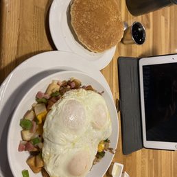 Breakfast bowl - A breakfast meal featuring eggs, hash browns with ham and green peppers, and a side of pancakes, served on white plates.