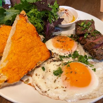 Medina Cafe - Le Complet: 2 Sunny Eggs, Flatiron Steak, Caramelized Onion & Israeli Couscous, Roasted Red Pepper Chèvre Focaccia, Romesco, Organic Greens - Breakfast & Brunch Near Me - Vancouver, British Columbia