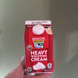 a hand holding a carton of cream