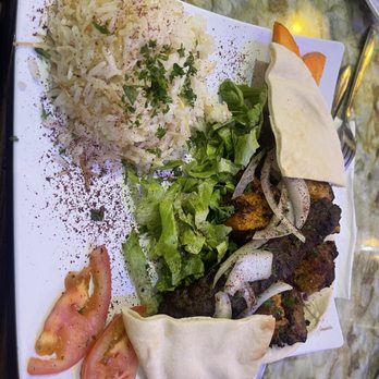 Hala Cafe - A meal featuring rice, fresh salad, grilled meat skewers, pita bread, and tomato slices, served on a white rectangular plate. - Mediterranean Near Me - Euless, Texas