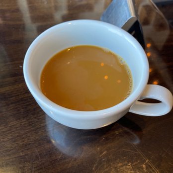 Coffee Plant Roaster - coffee - A white ceramic coffee cup filled with coffee sits on a dark wooden table, with a smartphone placed nearby. - Coffee & Tea Near Me - Eugene, Oregon