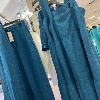 Dillard's - Blue linen dresses and matching pants are hanging on racks inside a retail clothing store, with other clothing items visible in the background. - Accessories Near Me - Melbourne, Florida