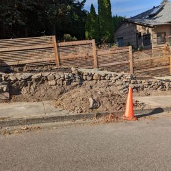 Vancouver Chimney and Masonry - There are missing rocks in the wall, a pile of dirt blocking the sidewalk, and a pile of dead branches. We paid $1950 for this.