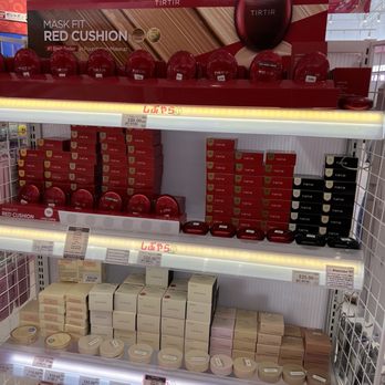 Shibuyala - Tirtir - The image shows a retail display shelf filled with TIRTIR makeup products, including cushion compacts in red and black packaging, and boxed items in white and beige. Price tags indicate costs such as $25.00, $18.00, $42.00, and $29.00. The shelf is organized with products stacked neatly, and the background features store ceiling lights and signage, suggesting a cosmetics section in a store. - Cosmetics & Beauty Supply Near Me - Arcadia, California