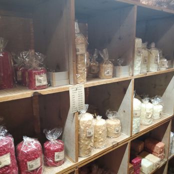 The Old Candle Barn - Shelves made of wood hold different types of candles and candle-making supplies, including wax blocks and jars, in a retail setting. - Candle Stores Near Me - Intercourse, Pennsylvania