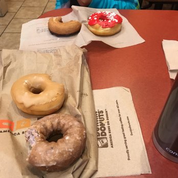 Dunkin' -  a woman sitting at a table with three doughnuts - Coffee & Tea Near Me - Nashville, Tennessee