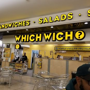 Which Wich - a man sitting at a table in a restaurant - Sandwiches Near Me - San Antonio, Texas
