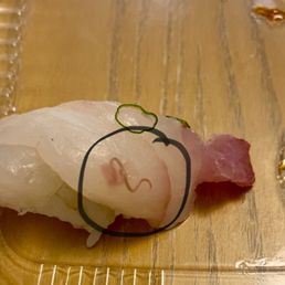 Piece of white fish sushi with a worm Piece of white fish sushi with a worm