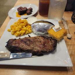 a plate of steak, macaroni and cheese, and a knife a plate of steak, macaroni and cheese, and a knife