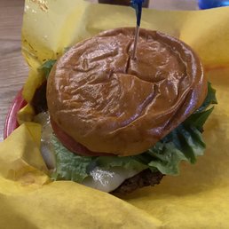 Impossible Burger - A burger with a homemade bun, lettuce, tomato, cheese, and a beef patty, served on yellow paper at a restaurant.