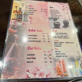 Sakura Grill - This menu displays a selection of Japanese beverages including beers like Sapporo, Kirin Ichiban, Heineken, and Corona, with prices for small and large sizes. It also offers white wines (Chardonnay, Pinot Grigio, Sauvignon Blanc) and red wines (Cabernet, Pinot Noir, Merlot), all priced per glass and bottle. The sake options include house hot and cold sake, and various flavored sake, with prices listed. Soft drinks such as Ramune soda, Coke, Fanta, and ginger ale are available, along with juices and teas. The design features cherry blossom graphics, creating a floral theme. - Sushi Bars Near Me - Burke, Virginia