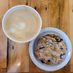 Lavender + Wildflower Latte in a paper cup, and a Lemon Blueberry Scone