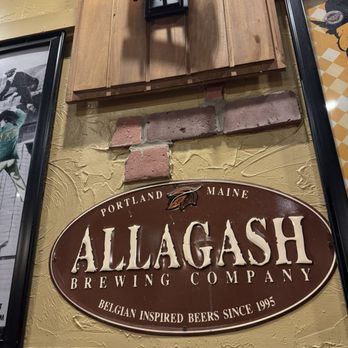Oscar's Alehouse - An oval sign for Allagash Brewing Company, featuring the text 'Portland Maine' and 'Belgian Inspired Beers Since 1995,' is displayed on a textured wall. - New American Near Me - Eldersburg, Maryland