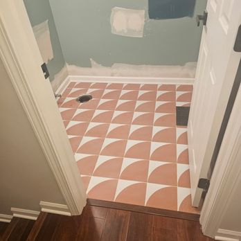 Premier Remodeling Services - A bathroom space with geometric patterned tile flooring, partially painted walls, and construction patches, indicating ongoing renovation work. - Flooring Near Me - Morton Grove, Illinois