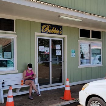 Bobbie's - a woman sitting on a bench in front of a restaurant - Hawaiian Near Me - Hanapepe, Hawaii