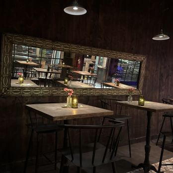 Crescent Ballroom - Mirror for neat view - A cozy restaurant interior features wooden tables with small vases of pink flowers and candles, reflected in a large mirror on a dark wood wall. - Music Venues Near Me - Phoenix, Arizona