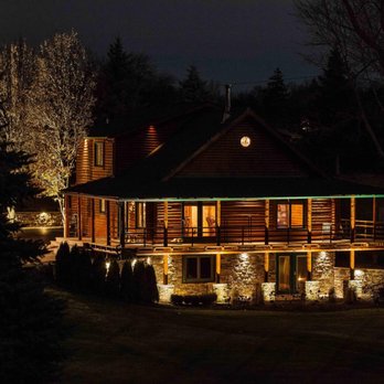 Progressive Irrigation - a log home lit up at night - Landscaping Near Me - Clarkston, Michigan Progressive Irrigation - a log home lit up at night - Landscaping Near Me - Clarkston, Michigan