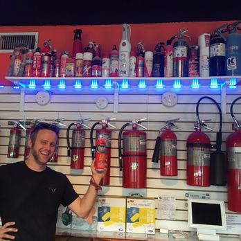 Longhorn Fire and Safety - Dustin shown here with my contribution to the wall of shame junk extinguishers (on the shelf above). - Fire Protection Services Near Me - Austin, Texas Longhorn Fire and Safety - Dustin shown here with my contribution to the wall of shame junk extinguishers (on the shelf above). - Fire Protection Services Near Me - Austin, Texas