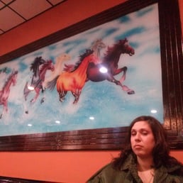 a woman sitting in front of a painting of horses a woman sitting in front of a painting of horses