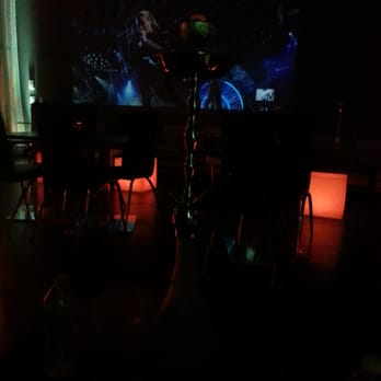 La Perle Hookah - a table and chairs in a dimly lit room - Hookah Bars Near Me - Wyandotte, Michigan