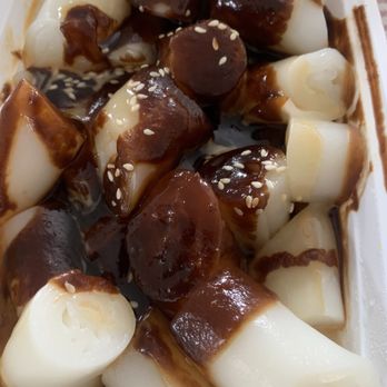 E Noodle - Rice roll with mixed sauces - Rice rolls with a dark sauce and sesame seeds, served in a white container, likely a Chinese dish. - Noodles Near Me - Brooklyn, New York
