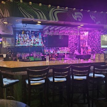 Hubble Hookah - A bar interior features a patterned wall, illuminated bottles on shelves, and hanging glassware, with seating at the counter. - Middle Eastern Near Me - Chicago, Illinois
