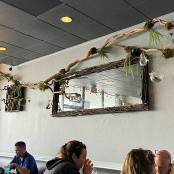 Coconut Rabbit - A branch hanging over a narrow mirror on the wall. - Thai Near Me - Los Alamitos, California