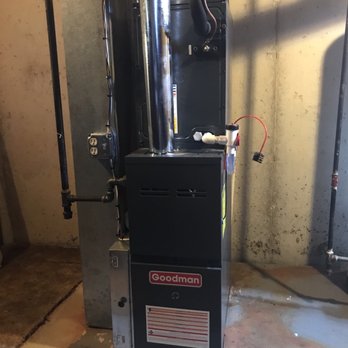 Air Adviser - New furnace - The image shows a Goodman furnace installed in a basement or utility room, with exposed concrete walls and floor. The furnace has a metal vent pipe connected to the top, and electrical wiring is visible on the side. The space appears functional, with pipes and electrical outlets nearby, indicating an HVAC installation for heating and air conditioning. - Heating & Air Conditioning/HVAC Near Me
