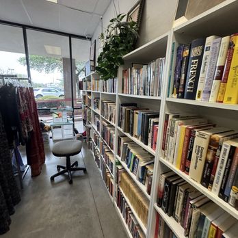 Goodwill - Interior of a bookstore or library with white bookshelves filled with books, a window showing parked cars outside, and a chair. - Bookstores Near Me - Cedar Park, Texas