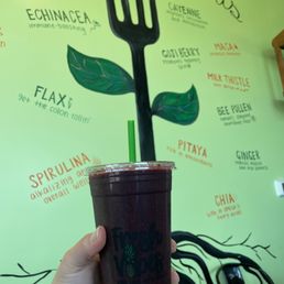 a hand holding a cup with a fork sticking out of it