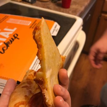 Little Caesars - a hand holding a half eaten pizza - Pizza Near Me - Statesville, North Carolina