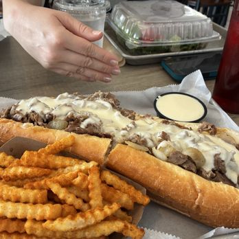 Nicky's Undefeated - I got the FRIES Old Bay with cheese sauce and the WHOLE Beef Cheesesteak w/extra cheese next to my sister's hand for sizing reference - Cheesesteaks Near Me - Tucker, Georgia