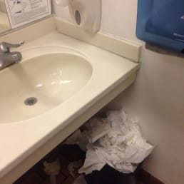 a sink with toilet paper on the floor