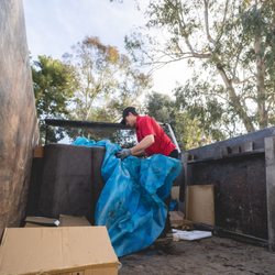Junk Dawgs Riverside - Setting up a furniture tarp over an old chair being moved.