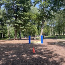East Longmeadow Bark Park - Benches, agility training tools such as ramps, trees, and a small fav park in the far background