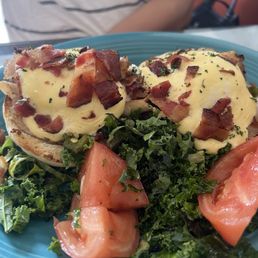 Poached eggs and kale and tomato salad with bacon bits on a home made English muffin.
