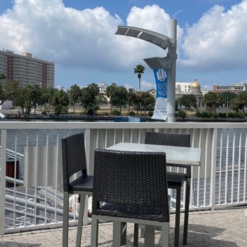 River's Edge - a woman sitting at a table with an umbrella - Seafood Near Me - Tampa, Florida
