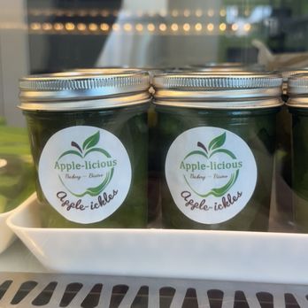 Apple-licious - Apple Pickles!! - Three jars labeled 'Apple-licious' are shown inside a refrigerated display case at a bakery or bistro. - Bakeries Near Me - Spring, Texas