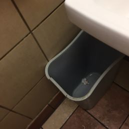 a sink and a trash can in a bathroom