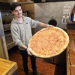 Benny Marconi's - One of the employees, Isaiah, holding the 28" pizza pie so you can compare the gigantic size pizza next to him.