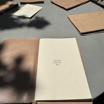 Father Forgive Me - Leather menu and round concrete table - Cocktail Bars Near Me - Detroit, Michigan